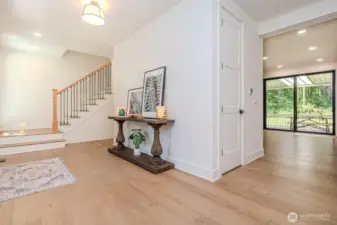 Stylish open-concept entryway with shiplap and designer lighting... Love he pretty stairway and railing. Notice the expansive slider to the backdeck just off the kitchen & great room! And ohhh... those wide plank engineered hardwoods are hard to resist!