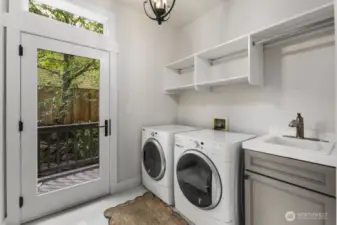 This laundry room is truly amazing!  Tall ceilings are an opportunity to personalize storage. Natural light floods this space through the large glass door from the backyard.