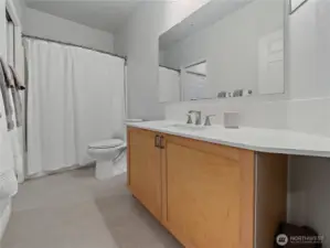 Quartz countertops, oversized mirror and deep storage under the sink complete this full bathroom.