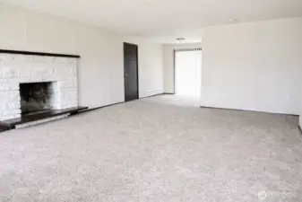 As you enter, find your living room with wood burning fireplace and kitchen to the rear. *Photo is from prior to current tenancy, home is fairly cluttered currently*