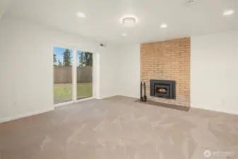 Large downstairs bonus room with sliding doors and wood burning fireplace.