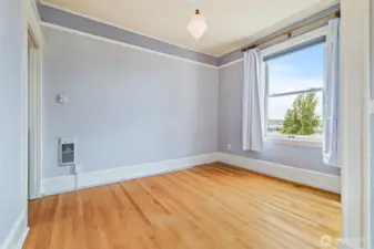 Charming bedroom with soft tones, hardwood floors, and a picture window framing Lake Union views.