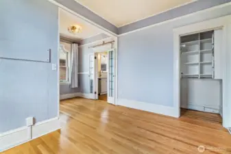 Hardwood flooring, soft lavender-gray walls, and windows with scenic water views create a cozy, sunlit space.