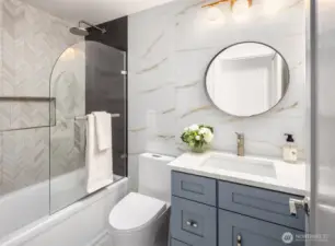 The stylish primary en-suite bathroom features dual vanities with updated hardware, ample counter space, and designer lighting. A shower-tub combo provides both functionality and relaxation, complemented by ceramic tile flooring.