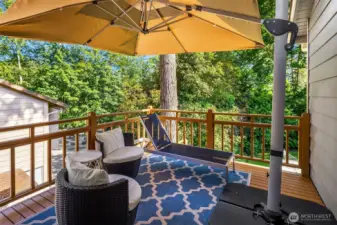 Relax and unwind on this private, tree-lined deck featuring all-day shade from a large umbrella, cozy lounge seating, and a stylish outdoor rug. Ideal for morning coffee or evening cocktails, this peaceful retreat offers a perfect blend of comfort and nature.