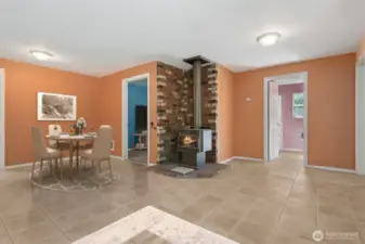 On this side of the living room, the star is the wood stove perched on a brick hearth that layers terracotta, cream, and deep tones. The scale of the room means you’ve got space to spread out, and you see the connections to more bedrooms beyond, which keeps the floorplan feeling open and livable.