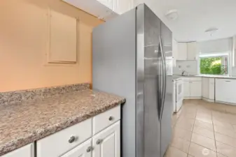 The fridge nook doubles as a pantry zone, with upper and lower cabinets giving you storage you’ll actually use. The electrical panel is neatly tucked here for easy access, and since the fridge stays, you are set up to use the kitchen on day one.