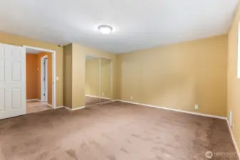 This angle shows just how open the 15 by 15 layout really feels. There’s space here for a full bedroom set without crowding, plus extra room to carve out a reading corner or desk zone. Natural light plays off the soft tan walls, and the mirrored closet doors bounce it back to make the room feel even larger. The latte carpet keeps it grounded and comfortable, so it’s equal parts functional and inviting.