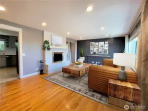 Upper level living room. Gleaming original oak hardwoods with fully updated trim and fireplace finishes. (Staged to Scale)