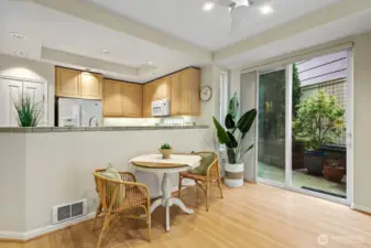 View from the living room to the open kitchen, dining area and you can see the slider leading out to the 2nd patio. This patio extends to the left the length of the unit. You can see the garden and flower pots that can fill this area.