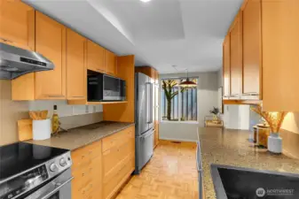Kitchen with parquet floors, stainless steel appliances, and eating area.
