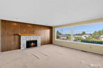 Living room with large windows shows off the beautiful views! Gas fireplace and mid-century style wall paneling.