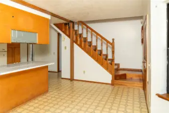 Kitchen eating space looking towards stairs to primary bedroom loft. Front door on right. Back door on left.