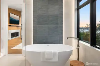 Free standing sculpture stone soaking tub perfectly framed by gorgeous floor to ceiling tile detail with custom motion activated LED back lighting