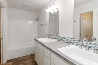Primary bathroom is complete with a double vanity and tub.