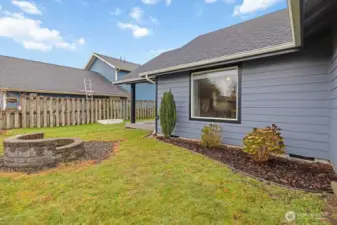Fenced Front yard boasts a custom firepit.