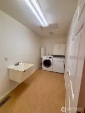 Laundry room with large wash basin, storage, and full size washer and dryer included. Linoleum floors in bathrooms and laundry room - easy care and durable.