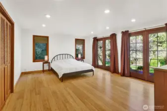 Gorgeous Primary Bedroom with a wall of French doors provide a beautiful back drop of nature and light. Warm bamboo flooring and a wall of closet space.