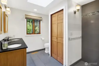 Remodeled Primary Bath with dual vanity and radiant tile floors and tilted shower with glass enclosure.