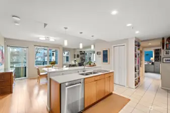 A reverse view from the Kitchen shows the Island, Dining and Living Rooms in the background, and Pantry Closet to the Right.  Down the Hall to the right is the Guest Bath and the Guest Bedroom.