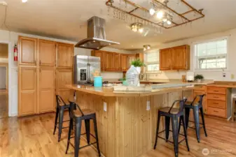 This kitchen is the heart of the home—warm, spacious, and designed for both everyday living and entertaining. Featuring an oversized island with bar seating, stainless steel appliances, and an abundance of cabinet storage, it’s perfect for meal prep or gathering with friends and family. Natural light pours in through large windows, highlighting the beautiful wood finishes and open layout. Whether you’re cooking up a feast or sipping your morning coffee, this inviting kitchen is sure to inspire.