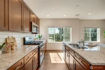 The chef-inspired kitchen is the star of the show, featuring stainless steel appliances, a gas range, sleek cabinetry, slab countertops, spacious eat-in island, and walk-in pantry.