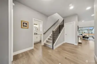 Wide open entry way with 5th bedroom to the left and powder room to the right of it.