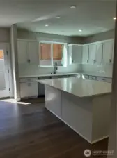 Bright kitchen featuring quartz counters, GE cafe gas range, dishwasher and microwave.