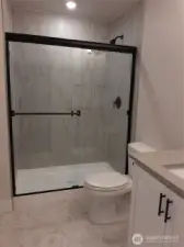 Lower level bath highlights upgraded matte black hardware throughout the home.