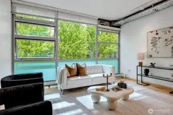 Floor-to-ceiling steel windows frame lush, park-like setting