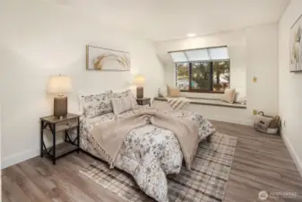 Spacious bedroom with solarium style window and bench seating.