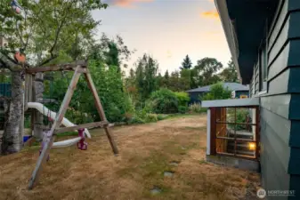 Side yard with play area and exterior entrance to lower level apartment.