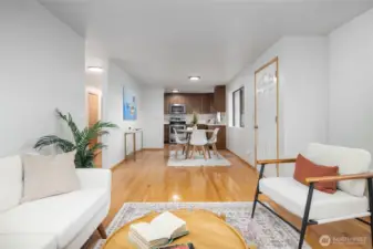 Living room, looking back to dining and kitchen. Hardwood floors.