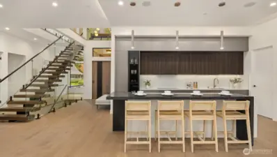 The primary kitchen showcases rich Italian walnut cabinetry, wide-plank white oak floors, honed Caesarstone countertops, and a full suite of Gaggenau appliances — including a 60" paneled refrigerator and induction cooktop.