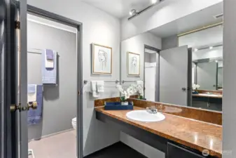 A 3/4 ensuite bath with wide vanity allows access to the sink while the shower is being used. Not seen is the large built-in medicine cabinet above the toilet, and a stack of drawers beneath the vanity.