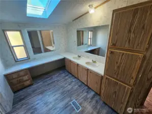 This en-suite bathroom is very roomy with double sinks and cupboards and counters.