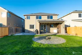 Large backyard featuring a covered area with a fireplace, plus a lush green space with a firepit for outdoor enjoyment