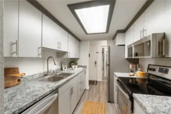 The galley kitchen offers plenty of cabinetry with handy slide-outs & decorative pulls. The stainless refrigerator is included