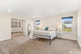Vast primary bedroom with a view of the french door leading to the walk-in closet