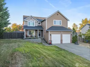 Large front yard, partially sloped. Lined with trees to block the views of main road