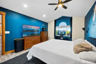 Primary bedroom with large window and ceiling fan.