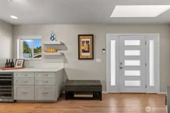 Bright and welcoming front entry featuring a frosted glass front door with matching sidelights and a skylight that fills the space with natural light.