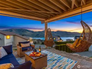 This covered outdoor living space is enhanced by electric see-through blinds that drop down from both of these deck beams for comfort, sun control, and privacy in this Lake Chelan view home.