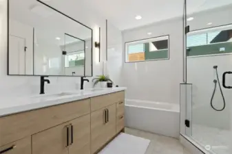 Sleek and contemporary bathroom showcasing double vanities for convenience, a luxurious soaking tub, and a spacious separate shower