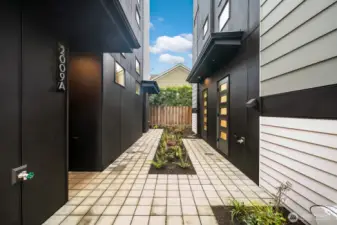 A landscaped paver walkway guides you from covered parking to the front steps, bordered by low-maintenance plantings. Photos are of model home 2009B.