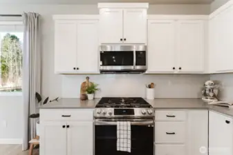 Upgraded kitchen featuring gas range, custom tile backsplash, and modern cabinetry.