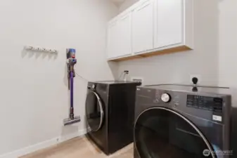 Dedicated laundry room with upper cabinetry for storage, and a convenient location near the bedroom and bathroom areas.