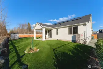 Back of home showcasing roof-mounted solar panels and energy-efficient exterior systems.