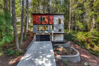 Welcome to 28 Hillside Pl. Contemporary exterior with clean lines, contrasting finishes, and a two-car garage set among mature evergreens.