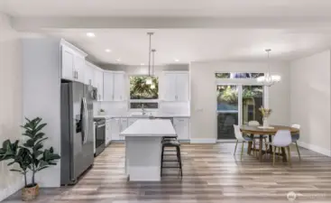 Open-concept kitchen and dining area with large island, stainless steel appliances, and access to outdoor space.